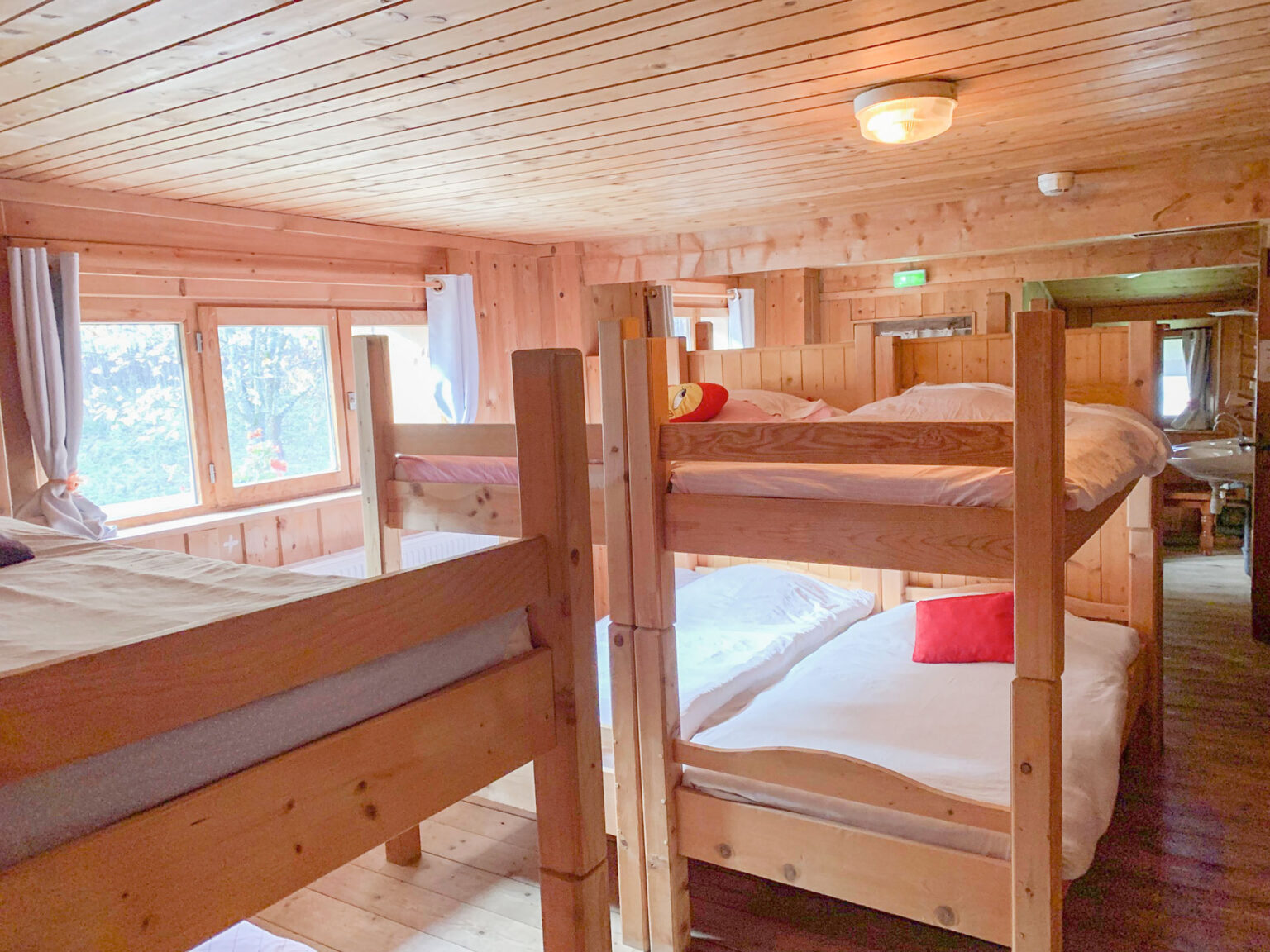 Au coeur des rêves au mont Chateleu détail du dortoir présentant les couchages en lit superposés, on voit les deux lavabos de la salle d'eau dans le fond de la pièce.